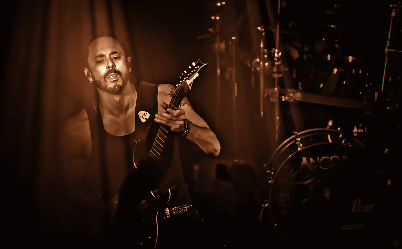 Marcelo Barbosa tocando guitarra num show do Angra, com o bumbo da bateria ao fundo