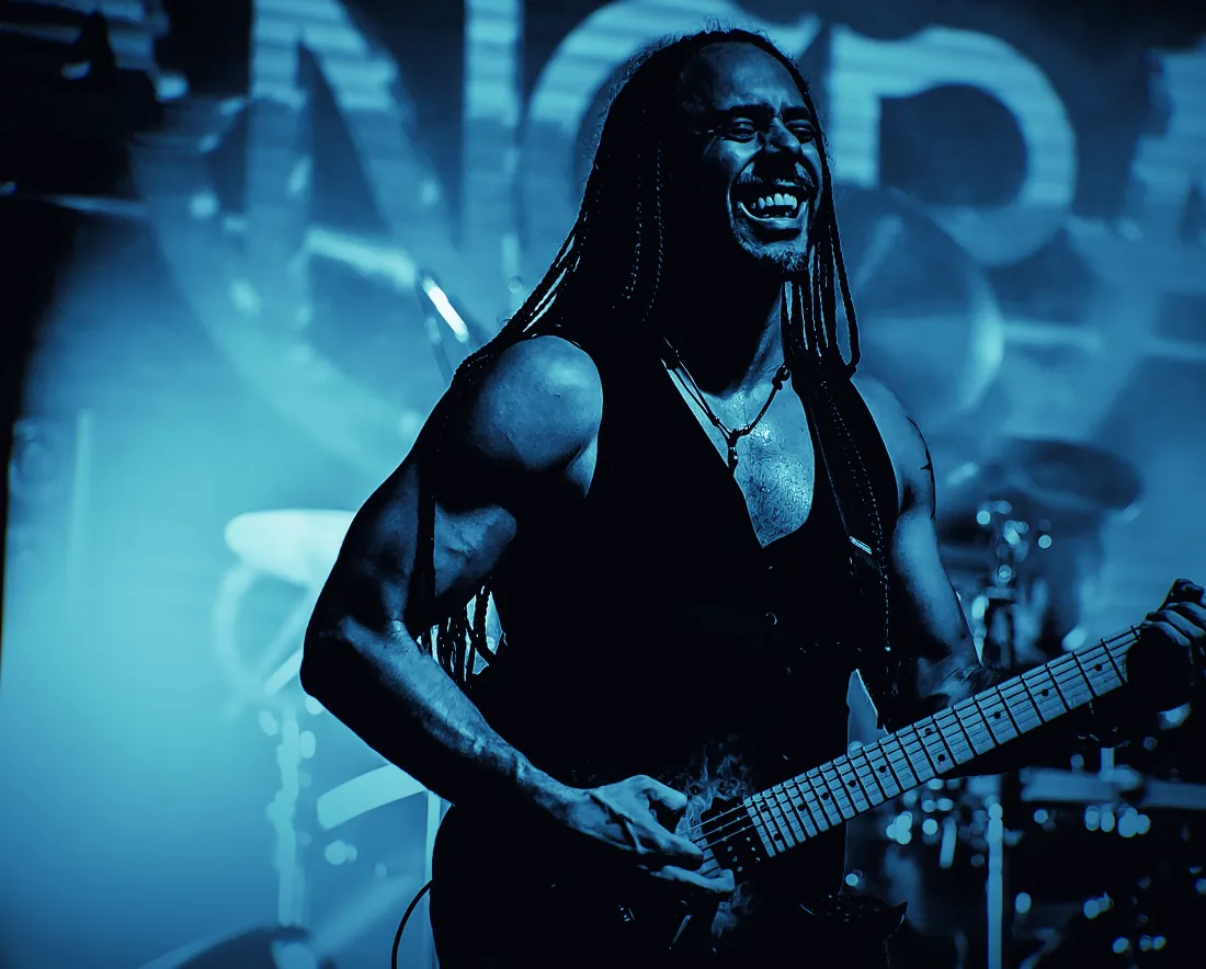 Marcelo Barbosa sorrindo enquanto toca guitarra num show do Angra