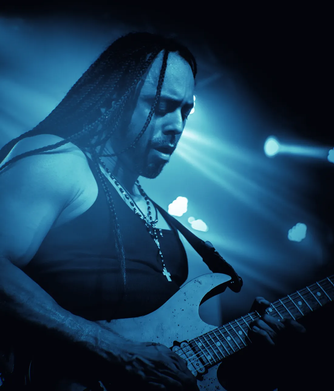 Marcelo Barbosa tocando guitarra ao vivo, sob luz azul de palco