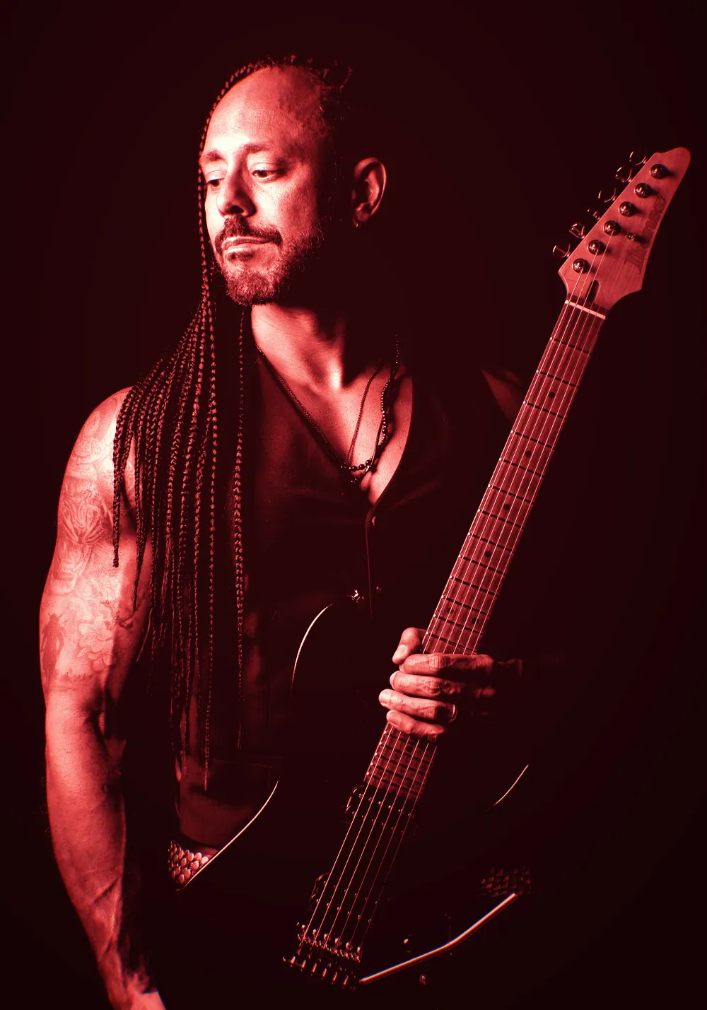 Marcelo Barbosa com a guitarra, em fundo escuro e luz vermelha